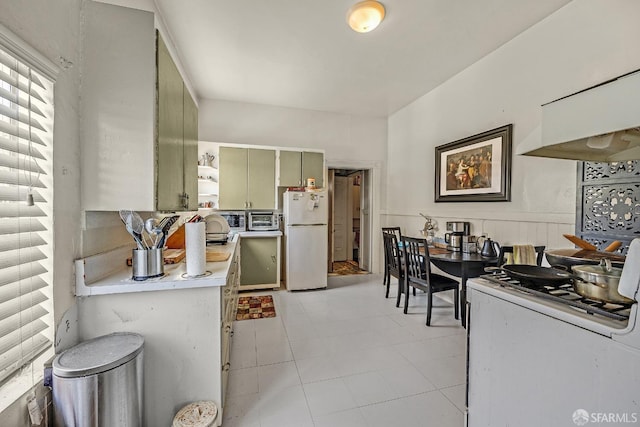 kitchen with light tile patterned floors, white appliances, and green cabinets