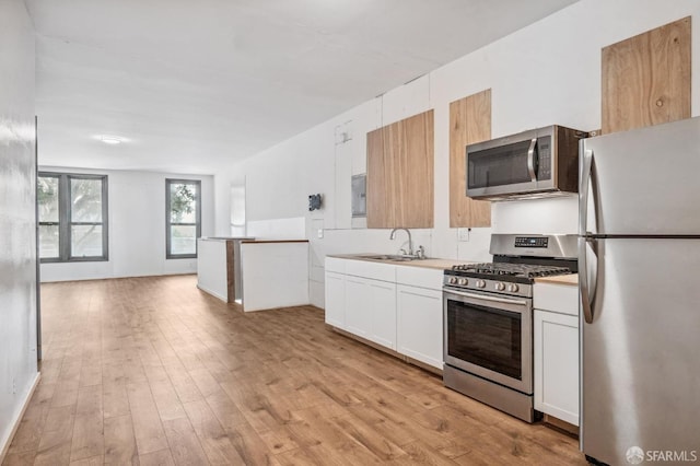 kitchen with light hardwood / wood-style flooring, stainless steel appliances, sink, and white cabinetry