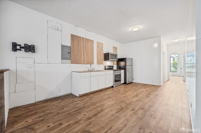 kitchen featuring white cabinets, electric panel, appliances with stainless steel finishes, and light wood-type flooring