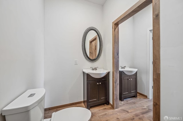 bathroom featuring wood-type flooring, vanity, and toilet