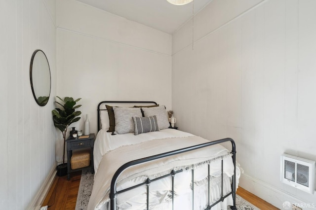 bedroom with heating unit and wood-type flooring