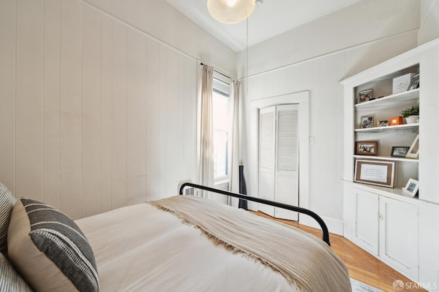 bedroom featuring hardwood / wood-style flooring, a closet, and wooden walls