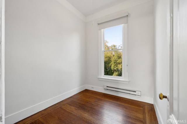 spare room featuring dark wood-type flooring, baseboard heating, ornamental molding, and plenty of natural light