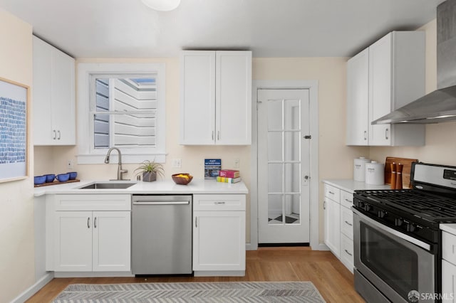 287 Staples Ave, San Francisco, CA 94112 - kitchen featuring stainless steel appliances, a sink, wall chimney exhaust hood, light wood finished floors, and white cabinets