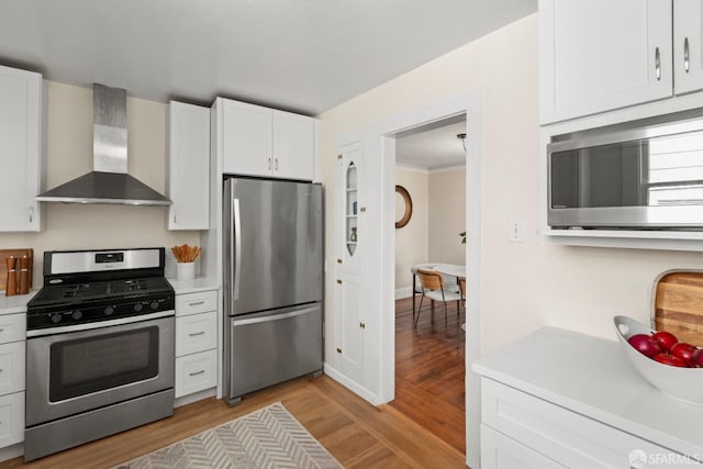 287 Staples Ave, San Francisco, CA 94112 - kitchen featuring appliances with stainless steel finishes, wall chimney range hood, light wood-type flooring, light countertops, and white cabinets