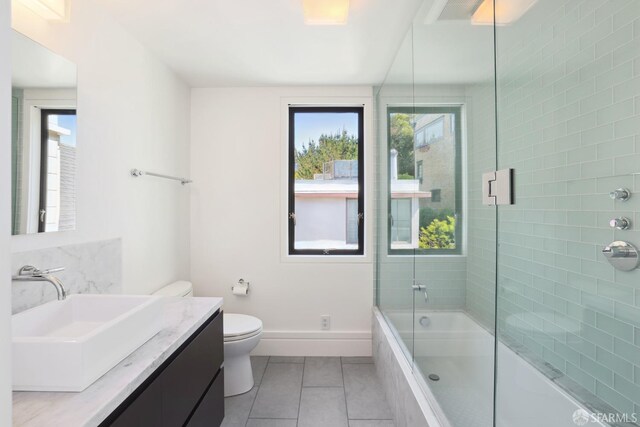 full bathroom with vanity, tile patterned floors, toilet, and a wealth of natural light