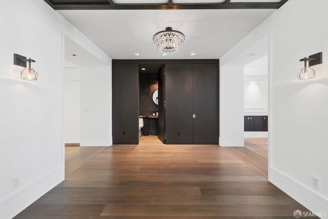 hallway with an inviting chandelier and wood-type flooring