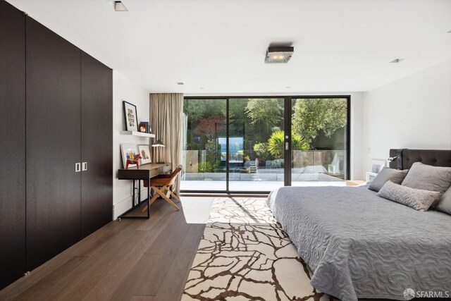 bedroom with a wall of windows, access to outside, and light hardwood / wood-style floors