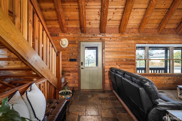 foyer entrance with beamed ceiling, a healthy amount of sunlight, wooden walls, and wooden ceiling