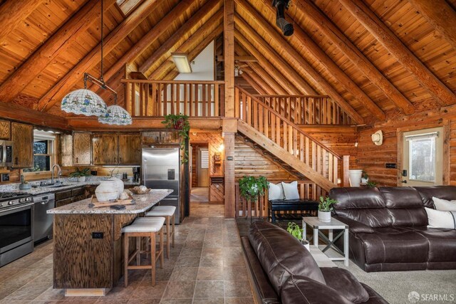 kitchen featuring wood ceiling, beam ceiling, a kitchen island, stainless steel appliances, and stone countertops