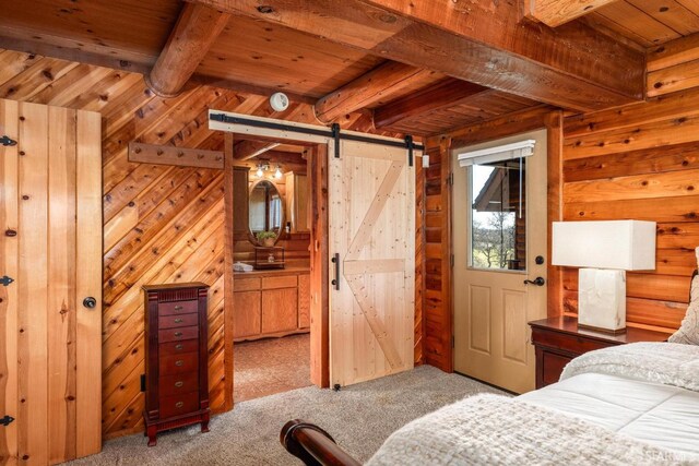 bedroom with beam ceiling, wooden ceiling, a barn door, and wood walls