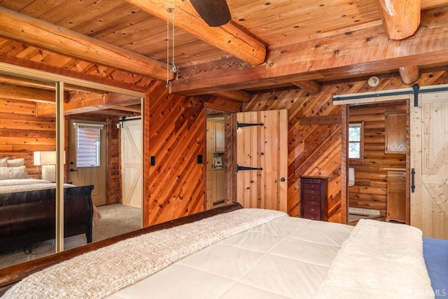 carpeted bedroom with rustic walls, a barn door, and beamed ceiling