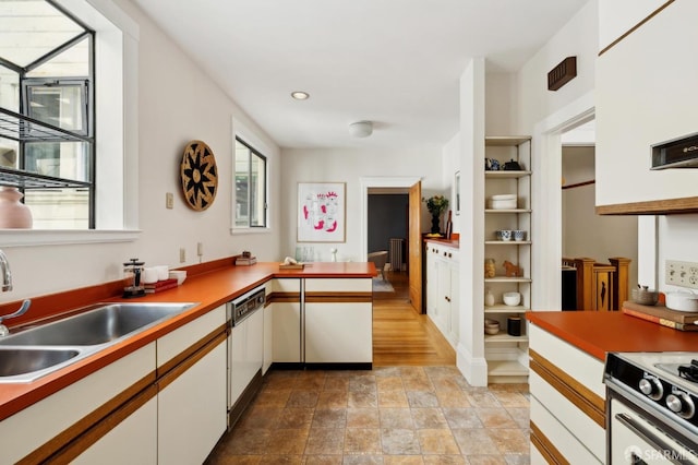 kitchen featuring built in shelves, gas range, white dishwasher, white cabinets, and a sink