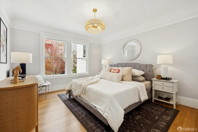 bedroom with light wood finished floors, crown molding, and baseboards