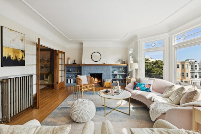 living area with a brick fireplace and wood finished floors