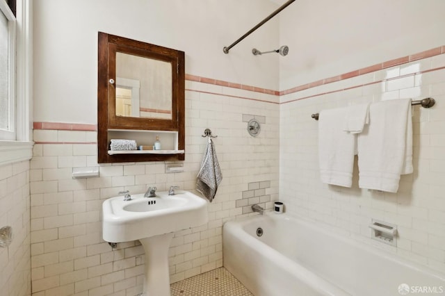 bathroom featuring wainscoting, shower / washtub combination, and tile walls