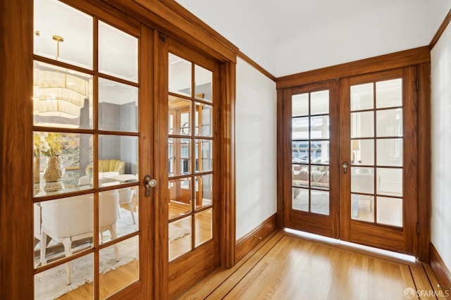 doorway featuring light wood-style flooring, french doors, and baseboards