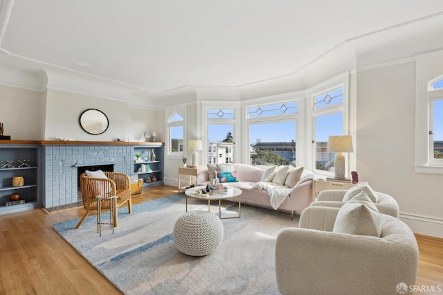 living area featuring a brick fireplace, crown molding, and wood finished floors