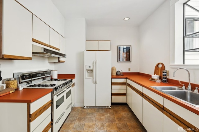 kitchen with under cabinet range hood, recessed lighting, white cabinets, white appliances, and a sink