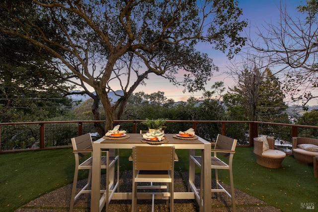 patio terrace at dusk with an outdoor fire pit and a lawn