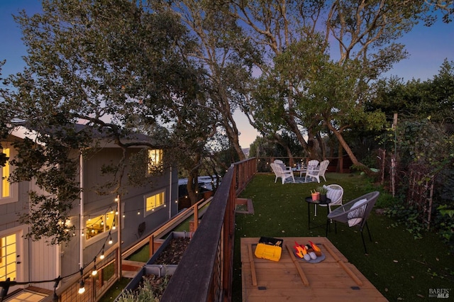 deck at dusk with a yard and an outdoor fire pit