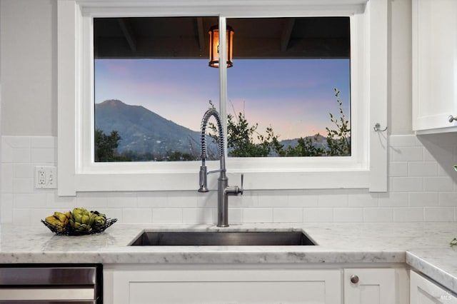 room details with sink, white cabinets, decorative backsplash, light stone counters, and a mountain view