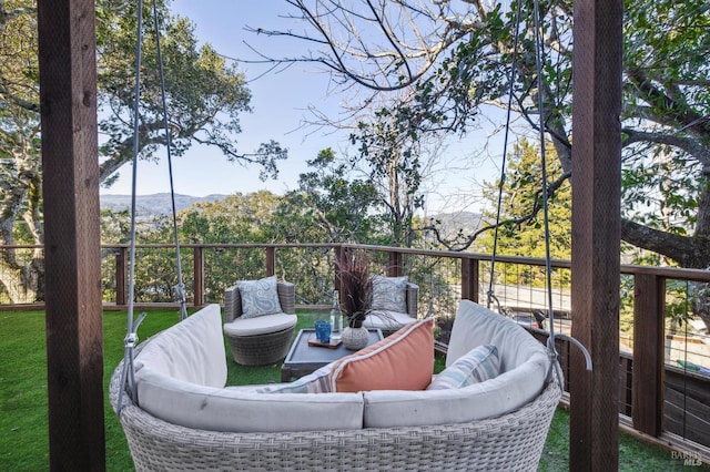 deck with a mountain view, an outdoor living space, and a lawn