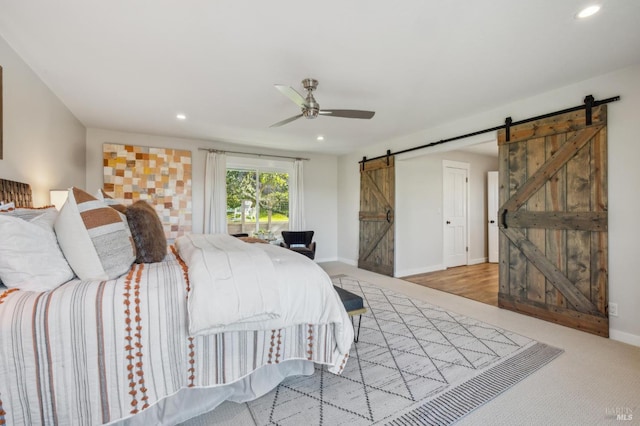 bedroom featuring light colored carpet, a barn door, and ceiling fan