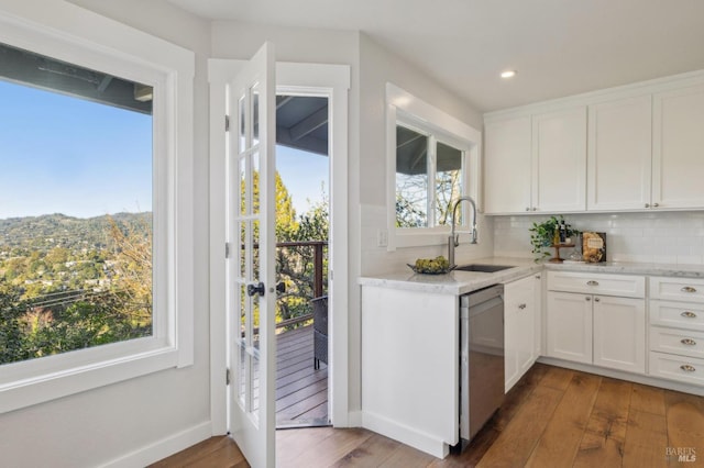 kitchen featuring sink, white cabinetry, dark hardwood / wood-style floors, decorative backsplash, and stainless steel dishwasher