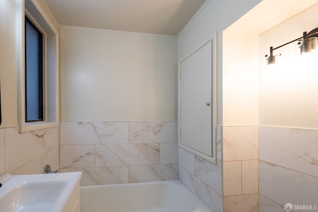 full bath featuring a tub, crown molding, tile walls, and a sink