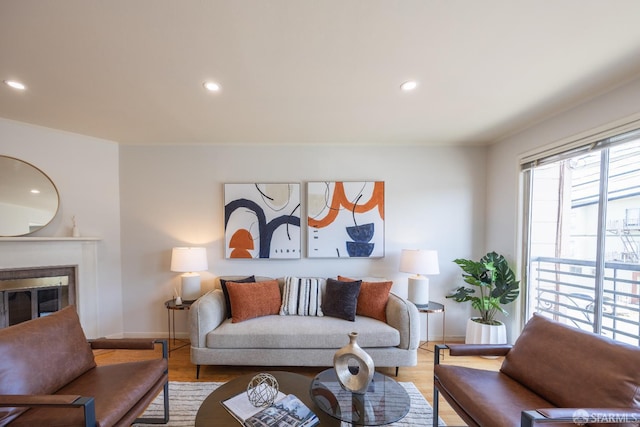 living area with recessed lighting, baseboards, wood finished floors, and a glass covered fireplace