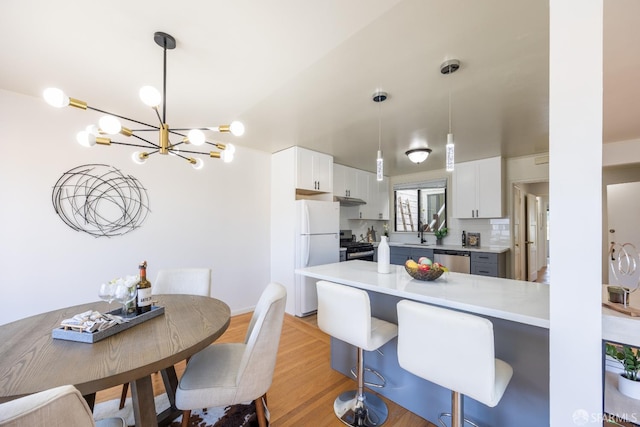 kitchen with stainless steel appliances, under cabinet range hood, a peninsula, a chandelier, and white cabinets