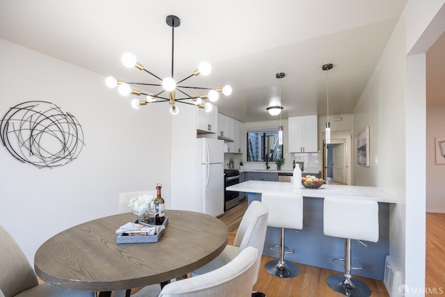 dining space featuring light wood-style floors and a chandelier