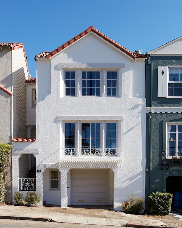 view of front of home featuring stucco siding, an attached garage, and a tile roof