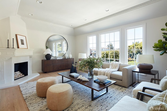 living area with light wood-style flooring, ornamental molding, a large fireplace, baseboards, and recessed lighting