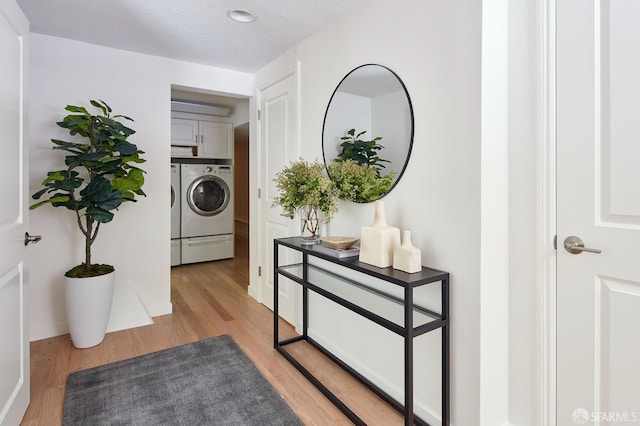 hall featuring independent washer and dryer, light wood finished floors, and baseboards