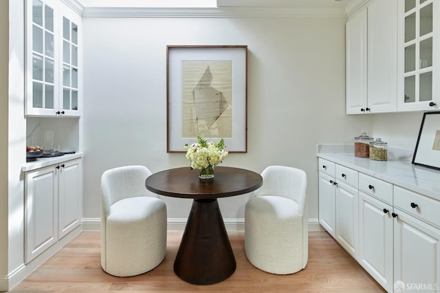 dining room with light wood-style flooring, ornamental molding, and baseboards