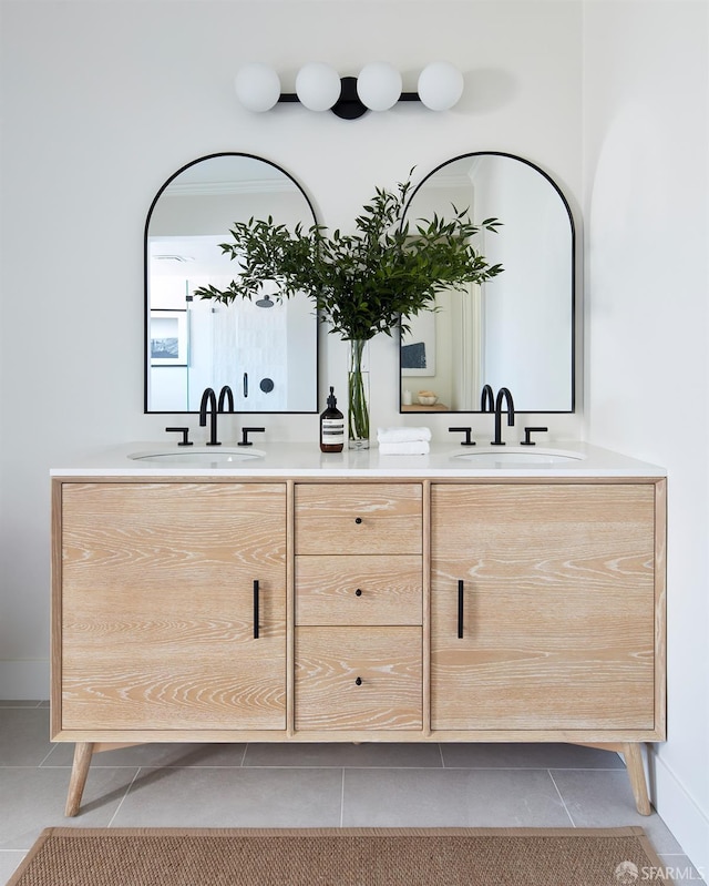 bathroom featuring tile patterned flooring, double vanity, and baseboards