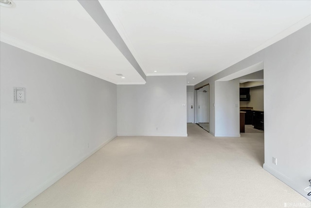 basement featuring baseboards, light colored carpet, and ornamental molding