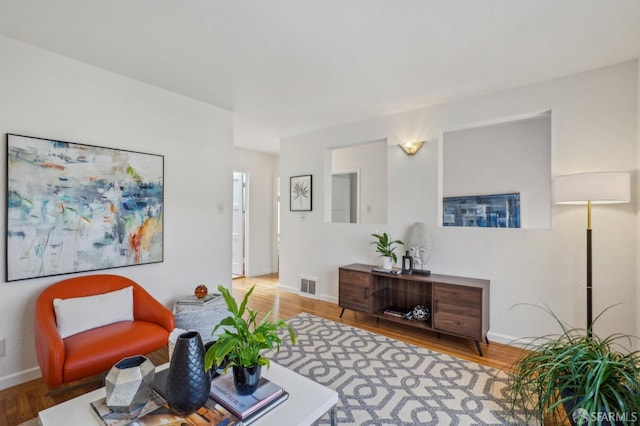 living room featuring baseboards, visible vents, and wood finished floors