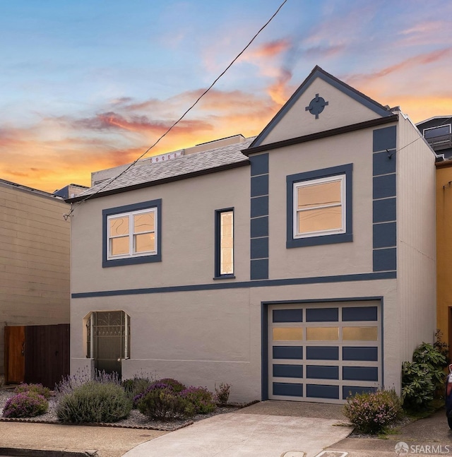 view of front facade with an attached garage, stucco siding, and driveway