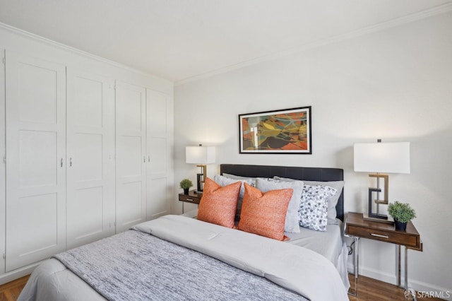bedroom featuring crown molding, baseboards, a closet, and wood finished floors
