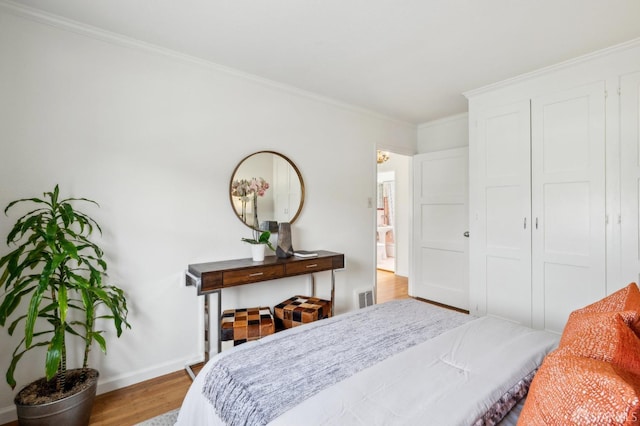 bedroom with crown molding, baseboards, visible vents, and wood finished floors