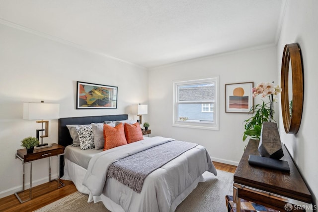 bedroom with crown molding, baseboards, and wood finished floors