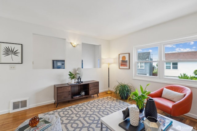 living area with baseboards, visible vents, and wood finished floors