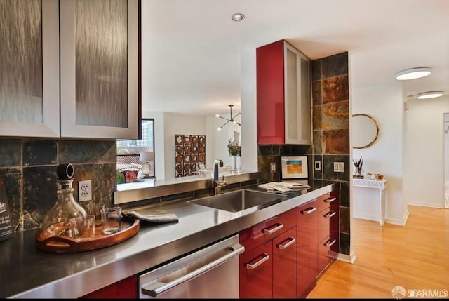 kitchen featuring backsplash, stainless steel dishwasher, sink, a notable chandelier, and light hardwood / wood-style floors