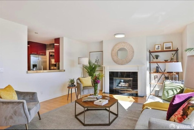 living room featuring a tiled fireplace and light wood-type flooring