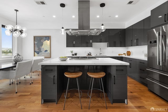 kitchen with island exhaust hood, a center island, stainless steel appliances, and hanging light fixtures