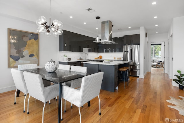 dining area featuring a notable chandelier, light hardwood / wood-style floors, and sink