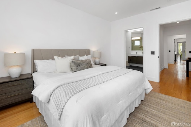 bedroom featuring light hardwood / wood-style floors and ensuite bath